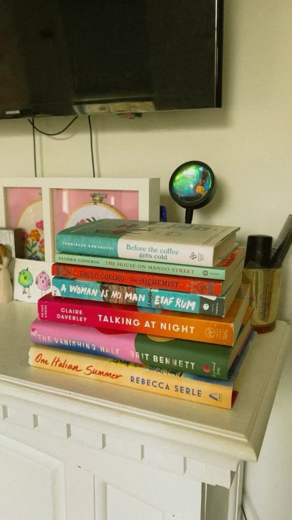 Stack of books on a white dresser — reading shelf